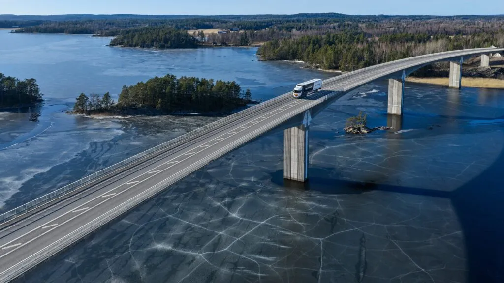 A Scania battery-electric truck driving across a bridge, representing the company’s shift towards a sustainable transport system.