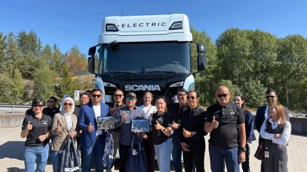 The Ekspres Perdana management delegation posing together with Scania representatives in front of a white Scania electric truck during their visit to Södertälje. (Photo: Ekspres Perdana/Facebook)