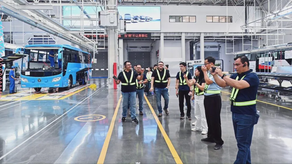 Overseas visitors wearing high-visibility vests taking photos during a factory tour inside a BAIC Foton bus assembly plant. (Photo: BAIC Foton)