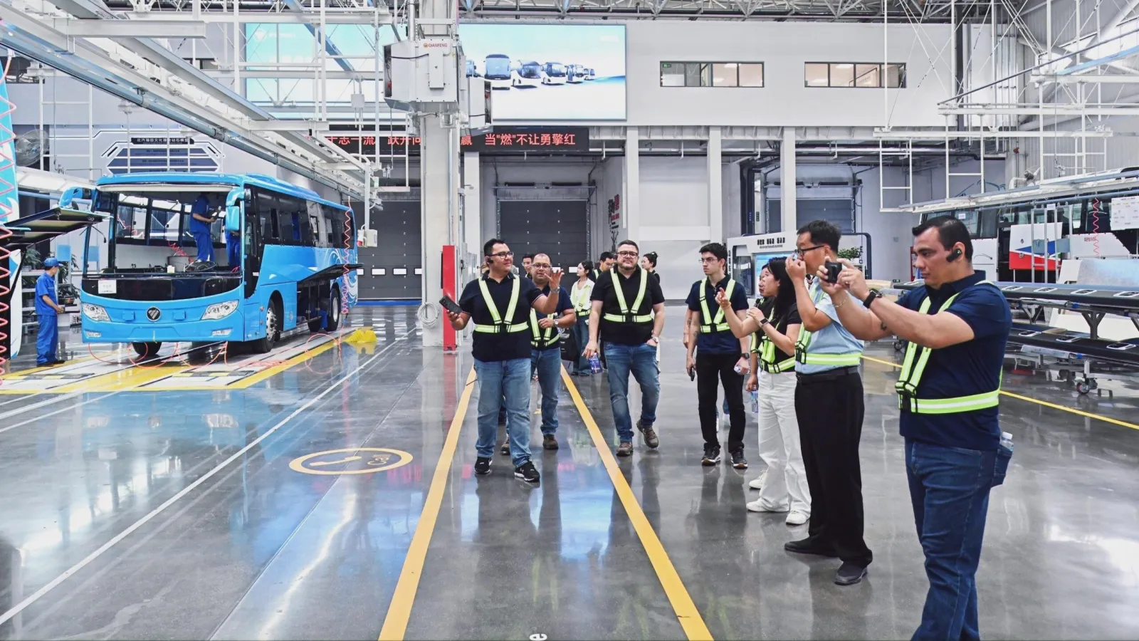 Overseas visitors wearing high-visibility vests taking photos during a factory tour inside a BAIC Foton bus assembly plant. (Photo: BAIC Foton)